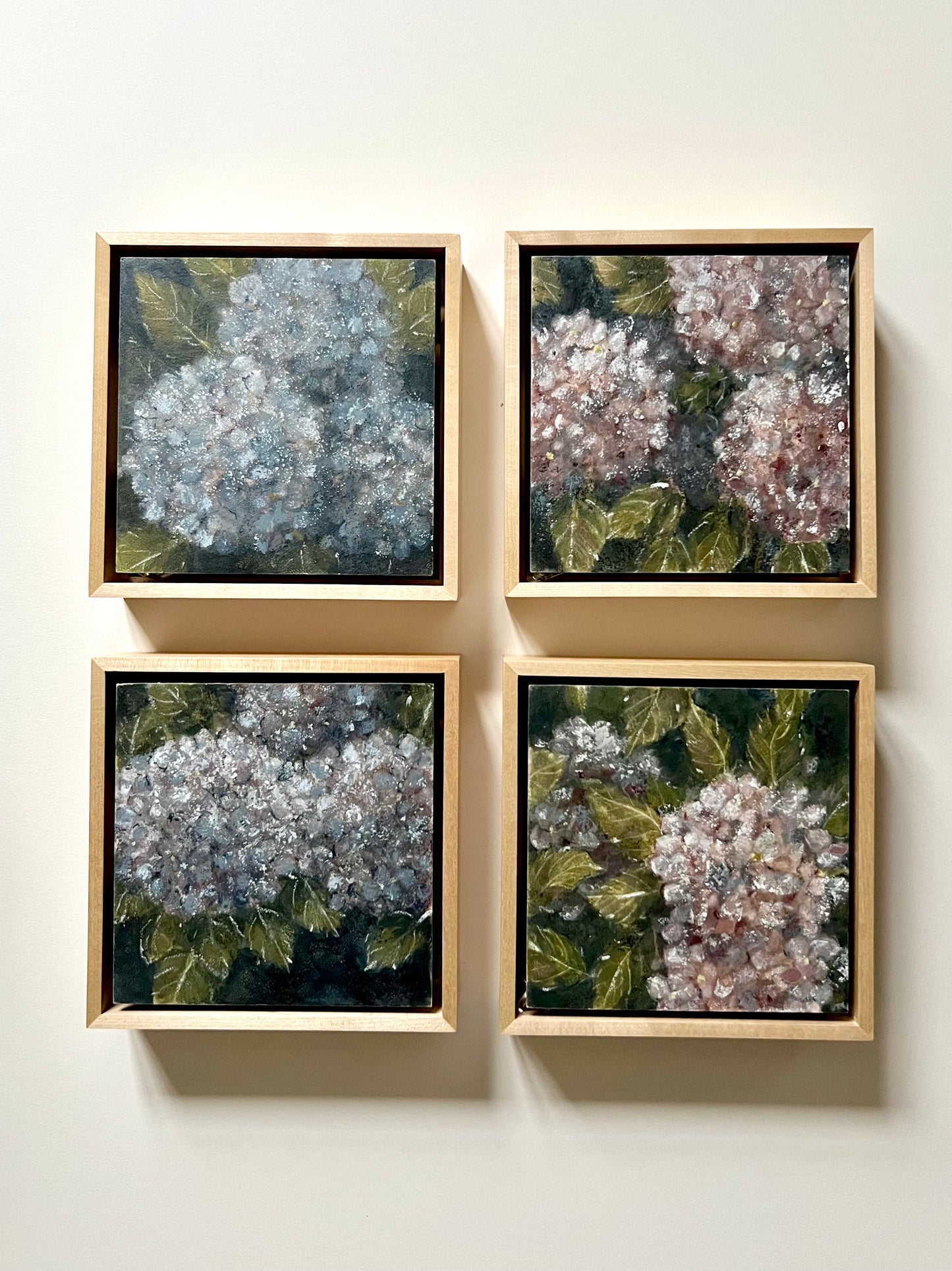 Four framed pictures of floral arrangements on a white wall.